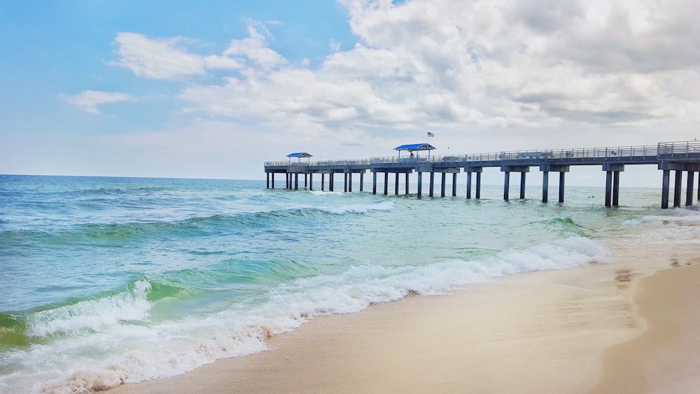 beach dock viewing sea under blue and white skies