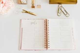 scissors and two paper clips beside opened spiral notebook