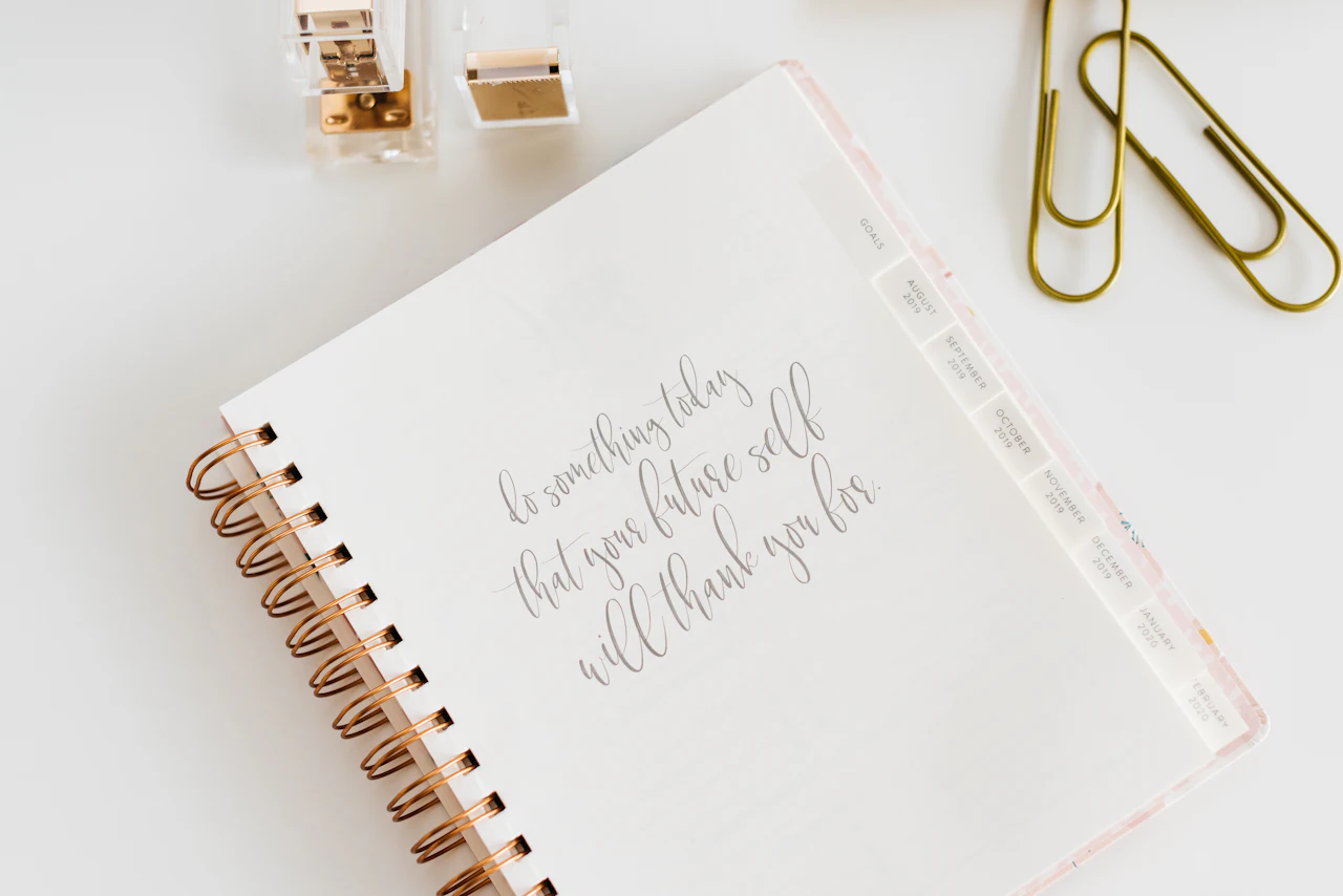 A white spiral notebook on a grey desk