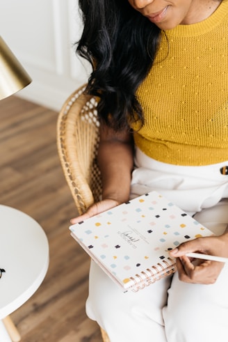 woman sitting on chair holding book and pen