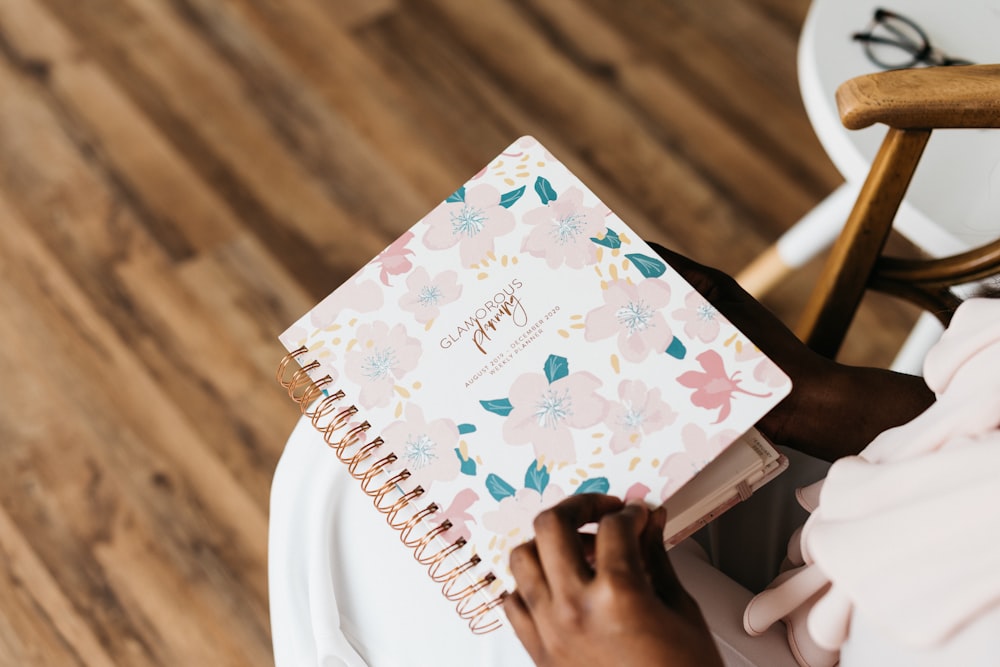 person in pink and green floral spiral notebook