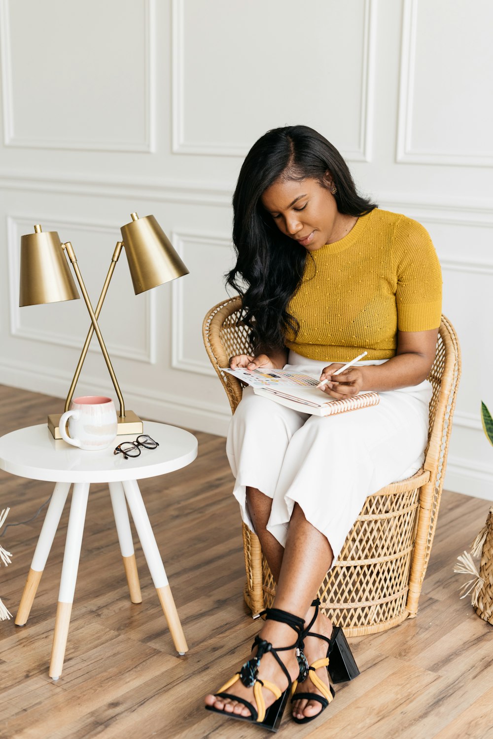 woman in yellow knit shirt sitting on rattan chair