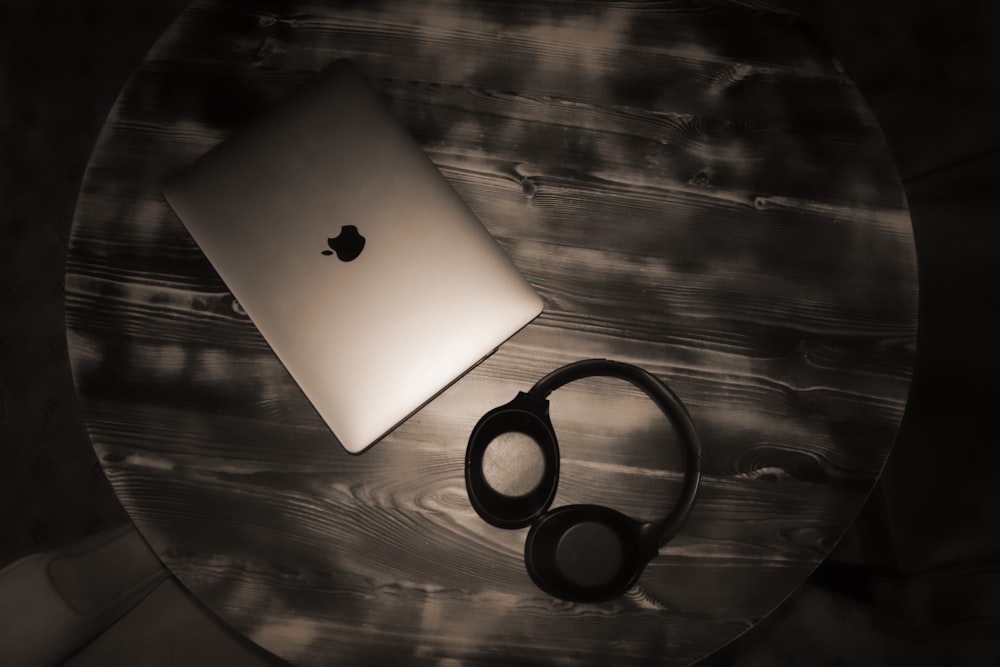 silver MacBook and black wireless headphones
