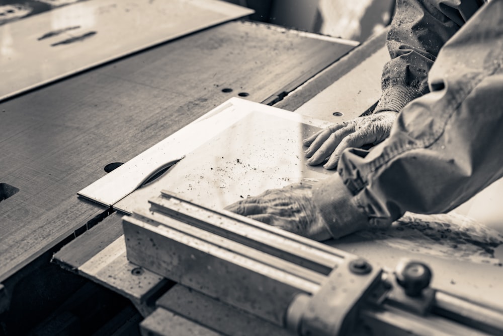 a person cutting a piece of wood with a machine