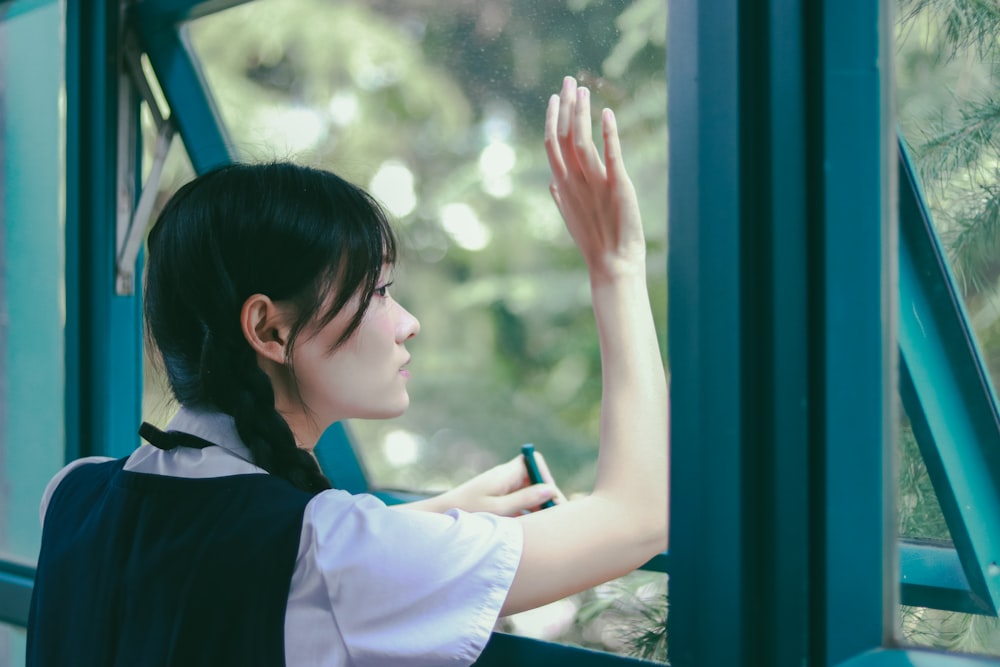 woman in school uniform looking outside window