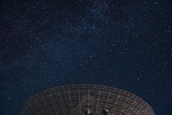 A subtle, minimalist illustration of a vintage radio telescope against a dark sky.