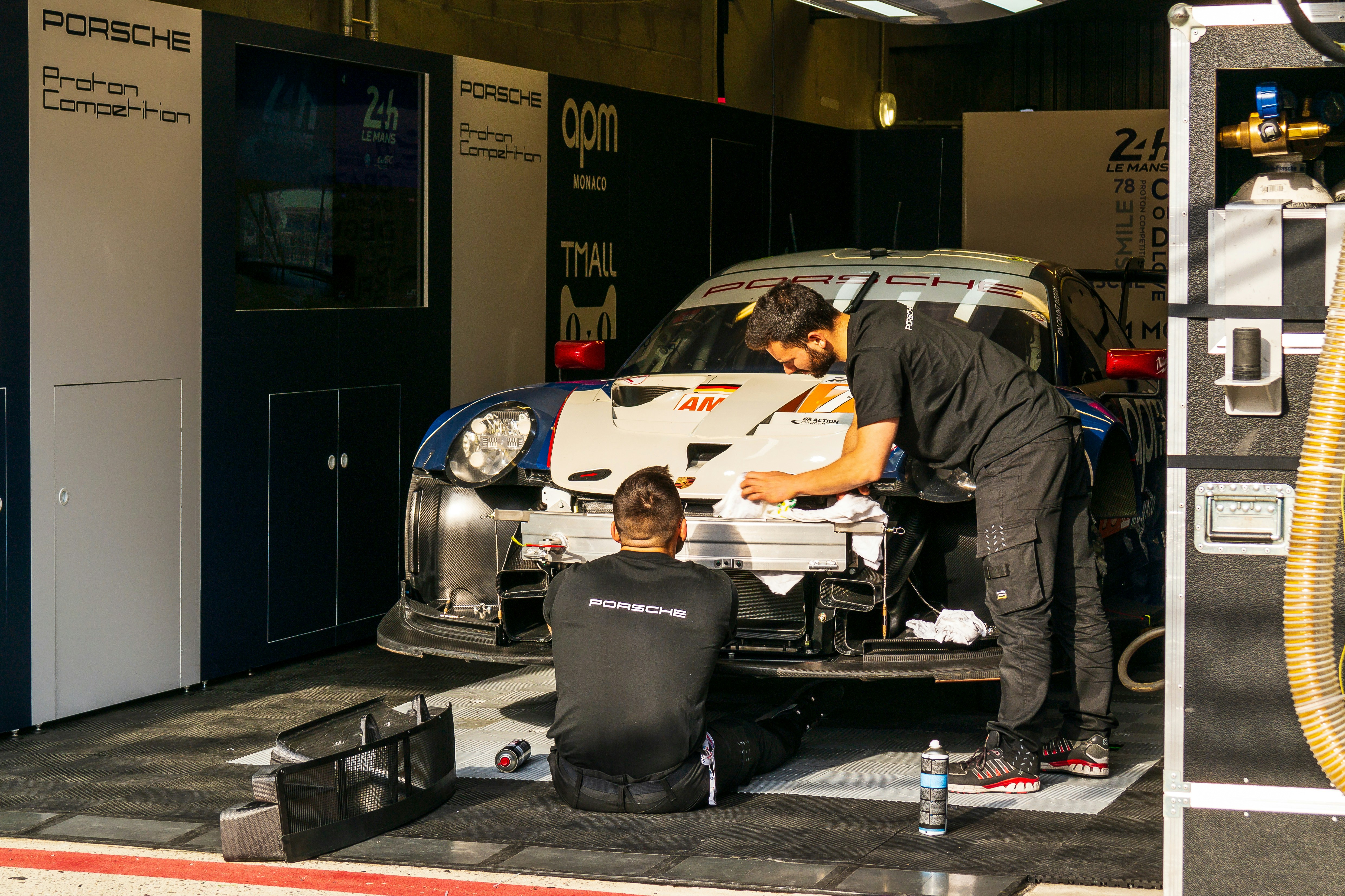 two men working on Porsche race car in pits
