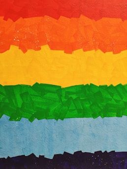 Brightly colored abstract painting with horizontal bands of red, orange, yellow, green, blue, and purple. Each color is applied with a textured, patchwork-like style, creating a visually striking effect.
