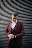 man in maroon suit looking at watch in wrist