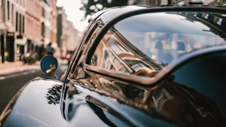 A glossy vintage car parked on a city street, showcasing its sleek design.