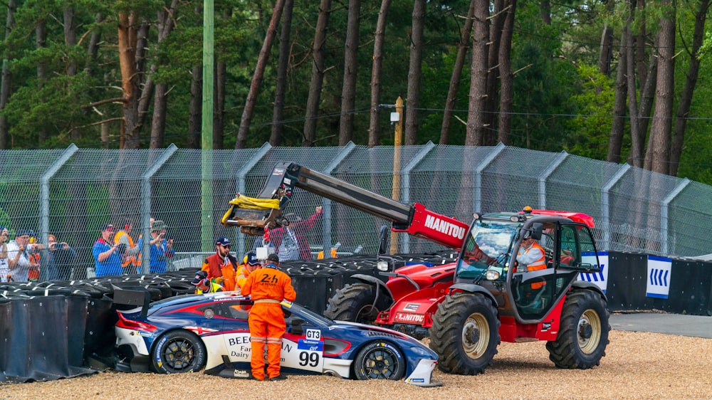 blue and white racing car beside man wearing red jumpsuit