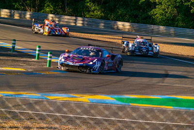 A thrilling shot of race cars speeding down the track under a bright blue sky.