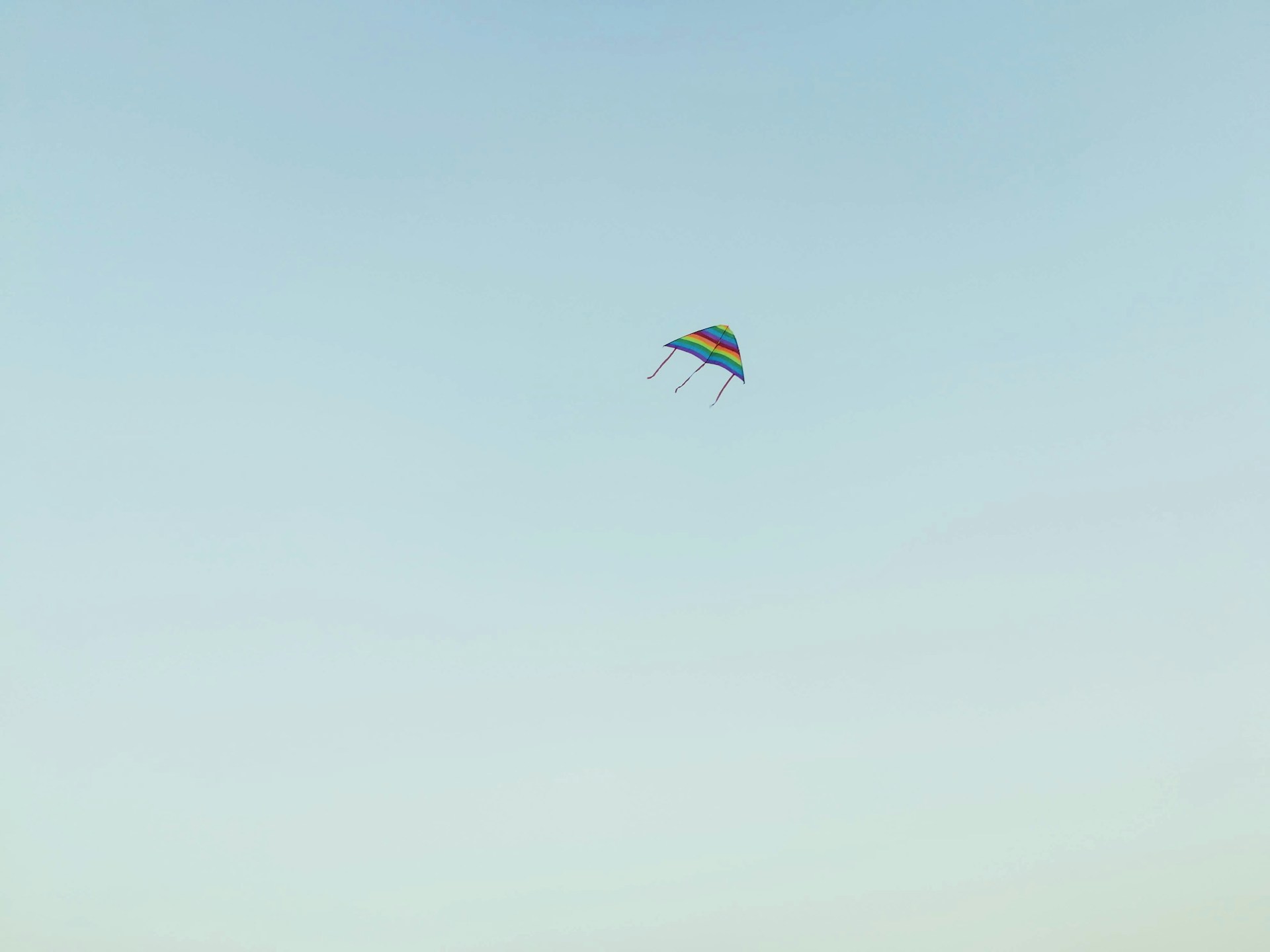 A close-up of a colorful kite soaring high in a clear blue sky.