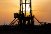 An oil rig at sunset symbolizing Enertrust's commitment to the energy sector.