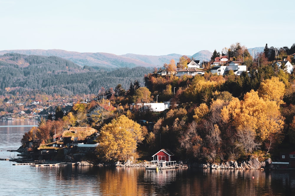 Maison rouge de 1 étage entourée d’arbres aux feuilles vertes au bord d’un plan d’eau