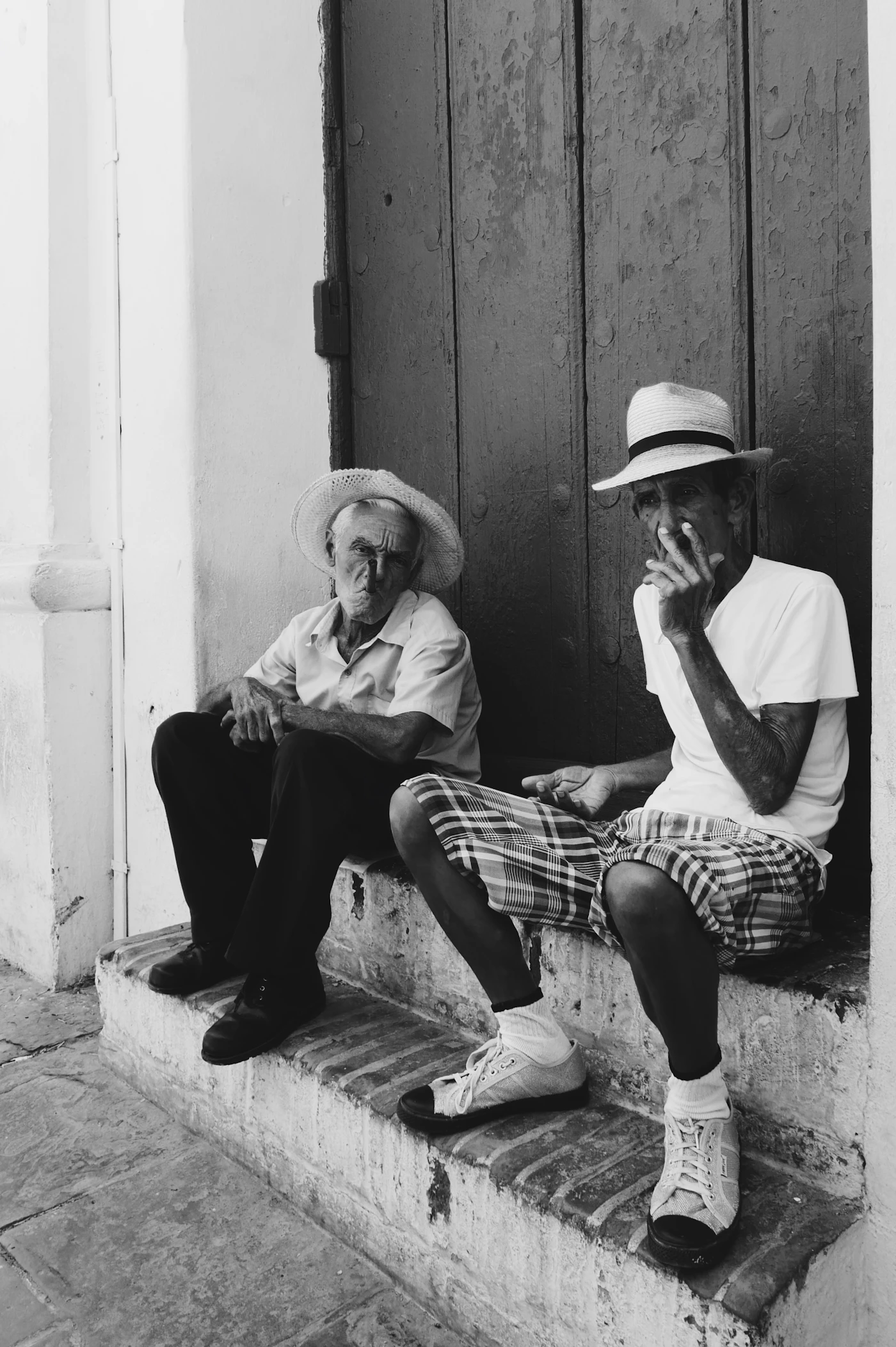 Dos hombres conversando en la puerta de una casa colonial en Trinidad, Cuba