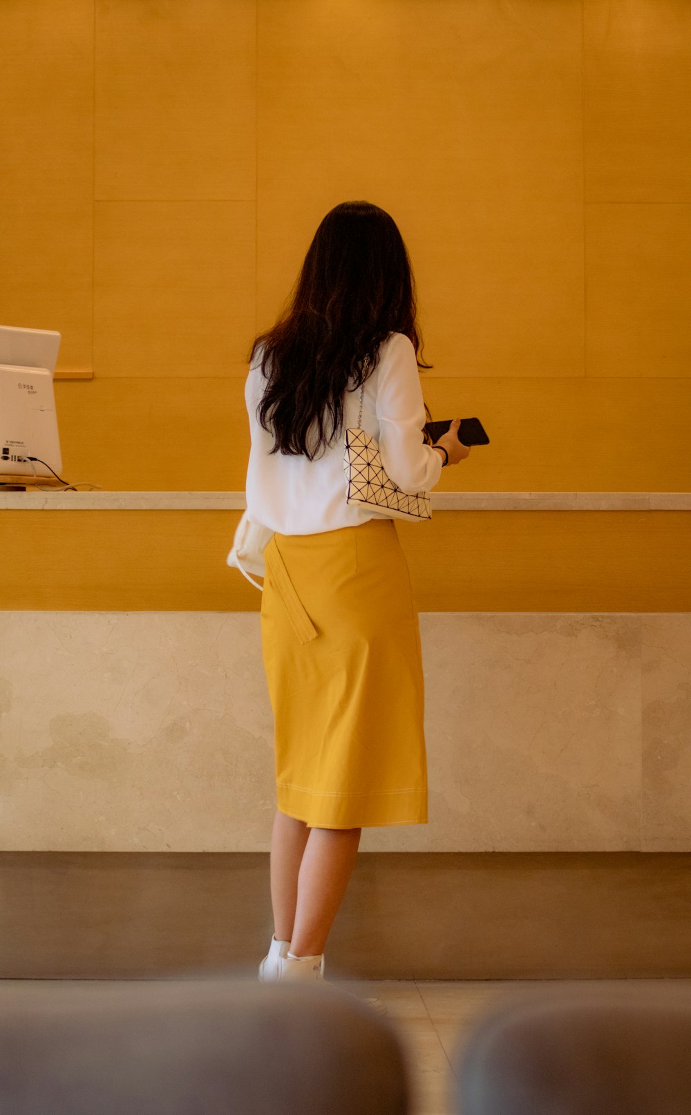 donna che indossa una camicia bianca a maniche lunghe e una gonna gialla