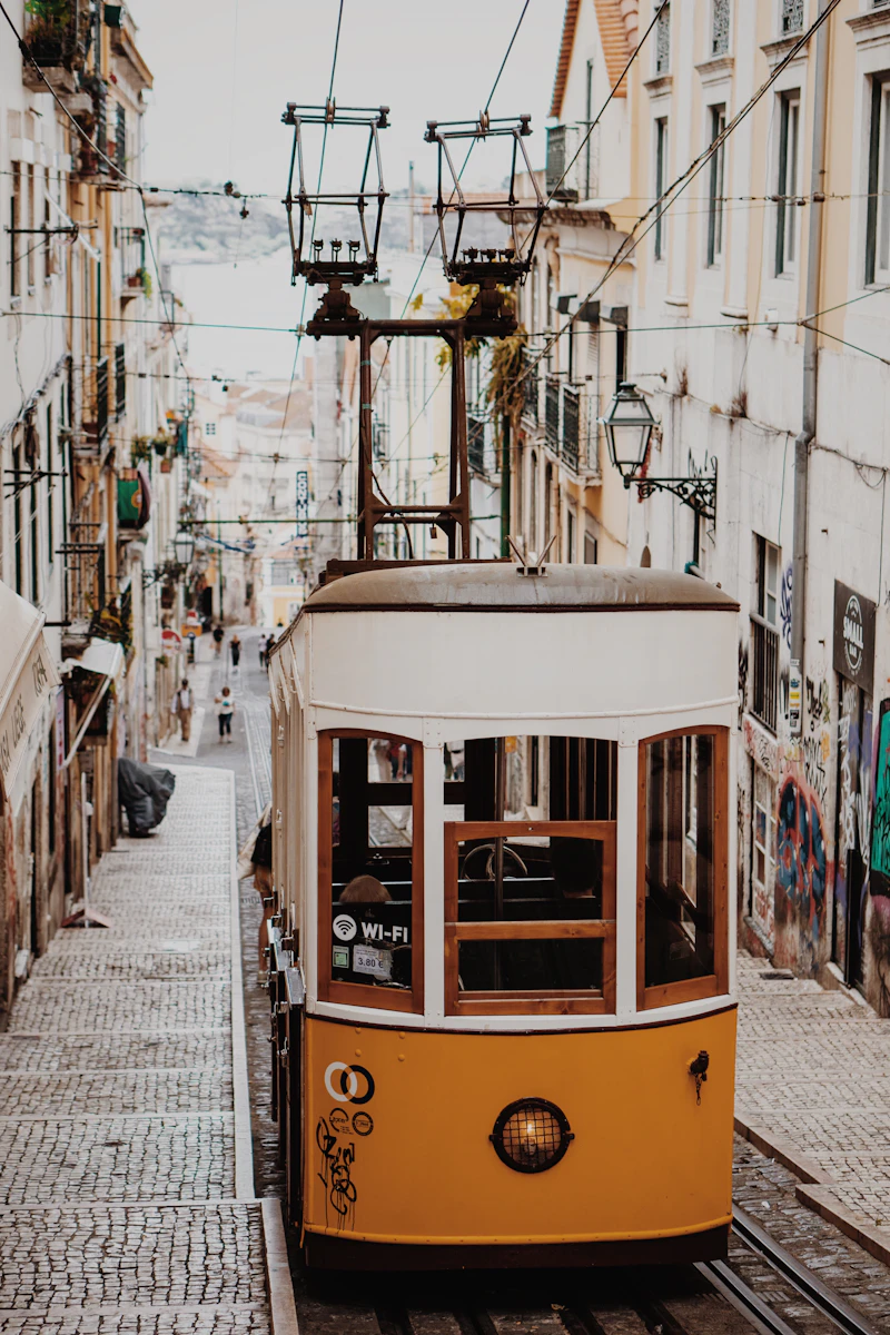 Yellow Lisbon tram passing a pastel building
