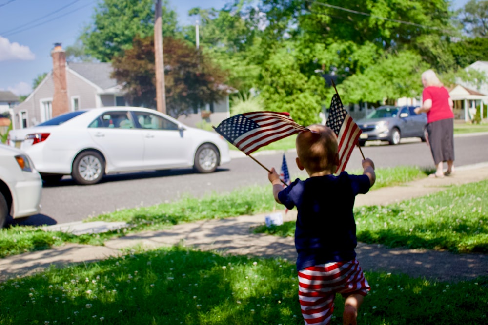 kid holding America flag during daytime