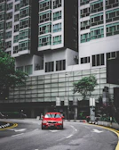 A vibrant red sedan cruising through a bustling city street at sunset