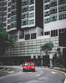 A bright red compact car ready for city driving with a backdrop of urban buildings.