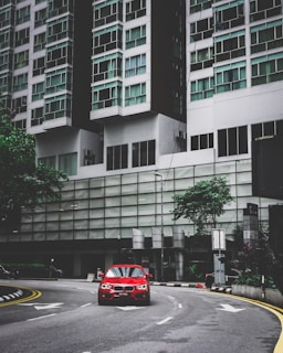 A bright red compact car ready for city driving with a backdrop of urban buildings.