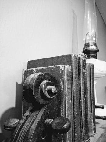 Close-up of a handcrafted metal bookend holding vintage books on a wooden shelf.