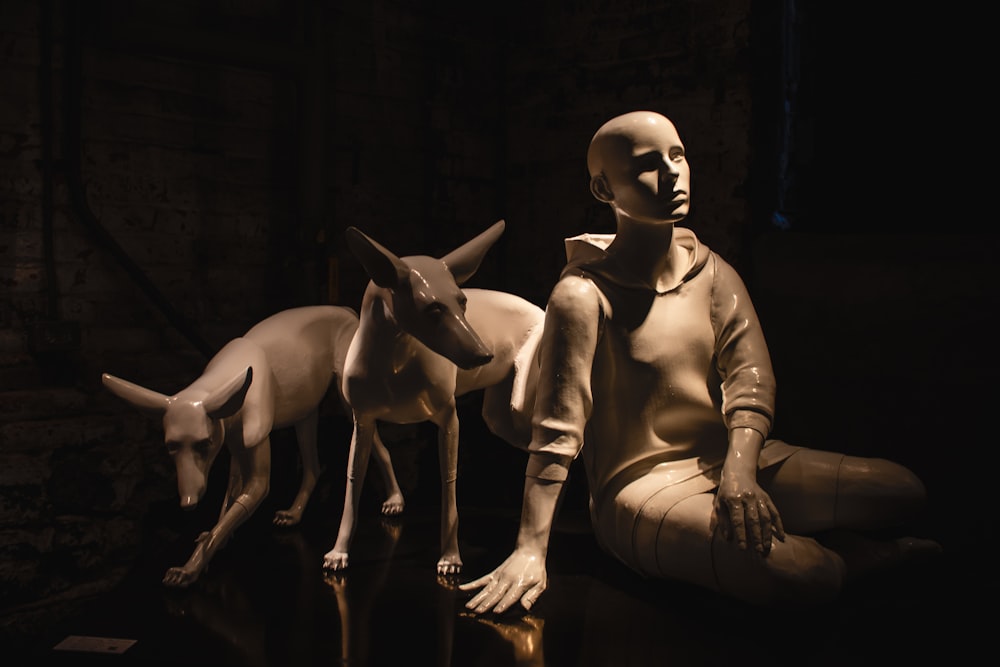 boy sitting beside two dogs statue