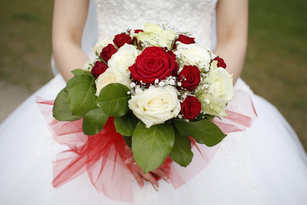 woman in white lace sleeveless dress holding bouquet of roses