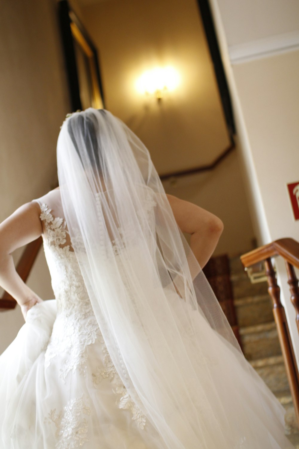 bride wearing gown and veil about to walk on staircase
