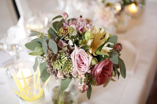 Close-up of a vibrant mixed bouquet with roses and eucalyptus on a rustic wooden table.