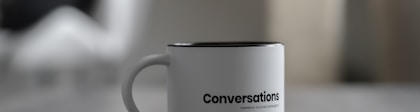 white conversations printed mug near smartphone