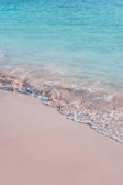 A peaceful turquoise wave gently washing over white sandy shore under a soft morning light.