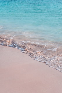 Turquoise waves gently tumbling onto the white sands of a secluded Caribbean beach at dawn.