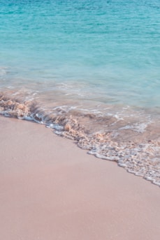 Calm turquoise waves gently washing over smooth beige sand.