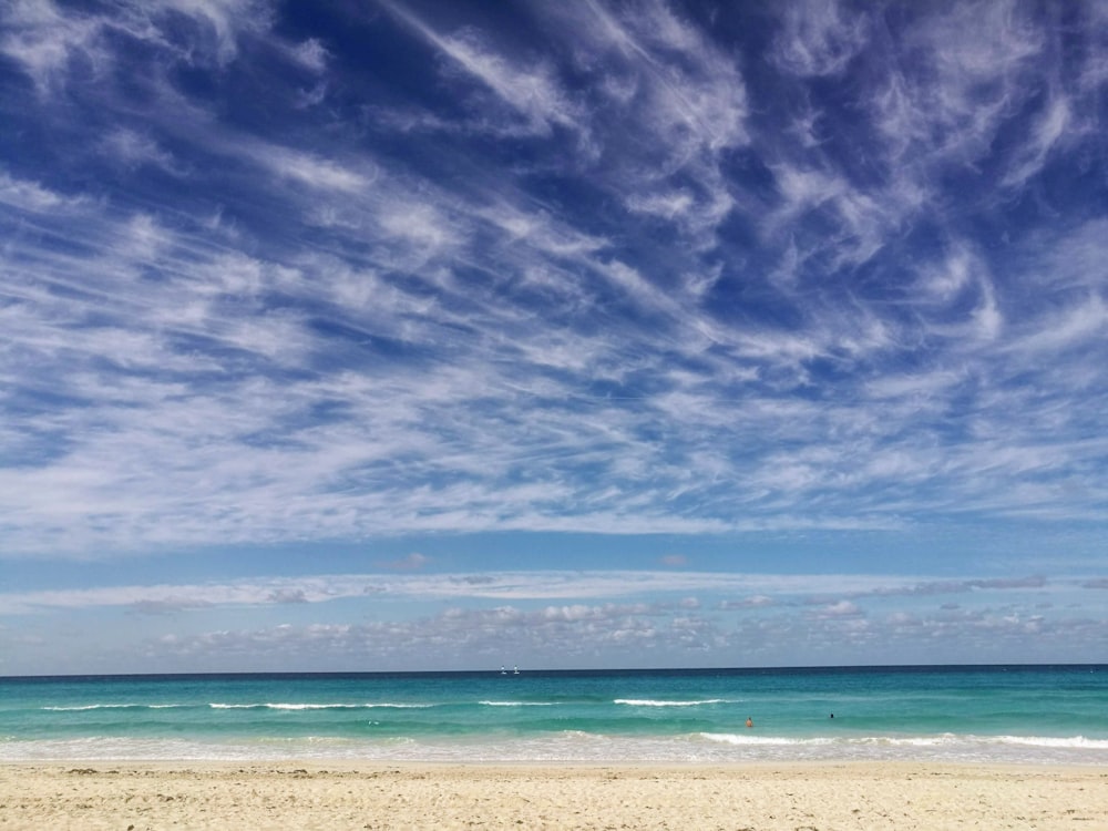 a sandy beach with a blue sky and ocean in the background