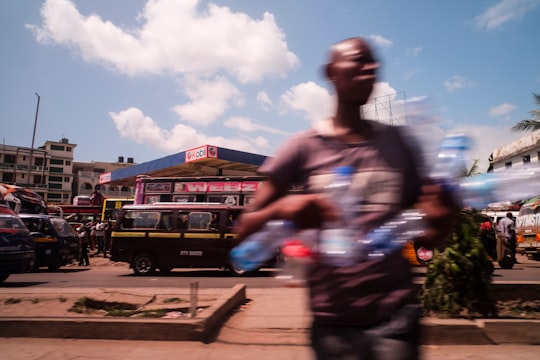 man holds empty water bottles while crossing the street in Mombasa Kenya