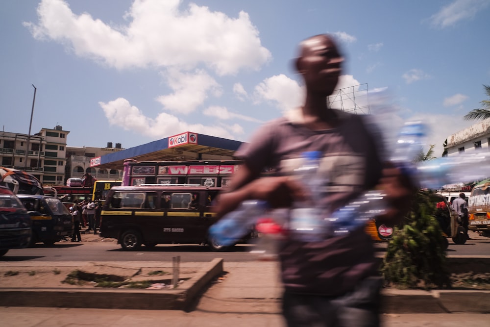 man holds empty water bottles while crossing the street