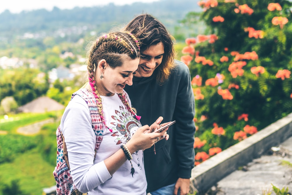 man and woman smiling looking at phone