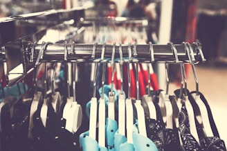 Close-up of trendy clothing items displayed on hangers in a bright store.
