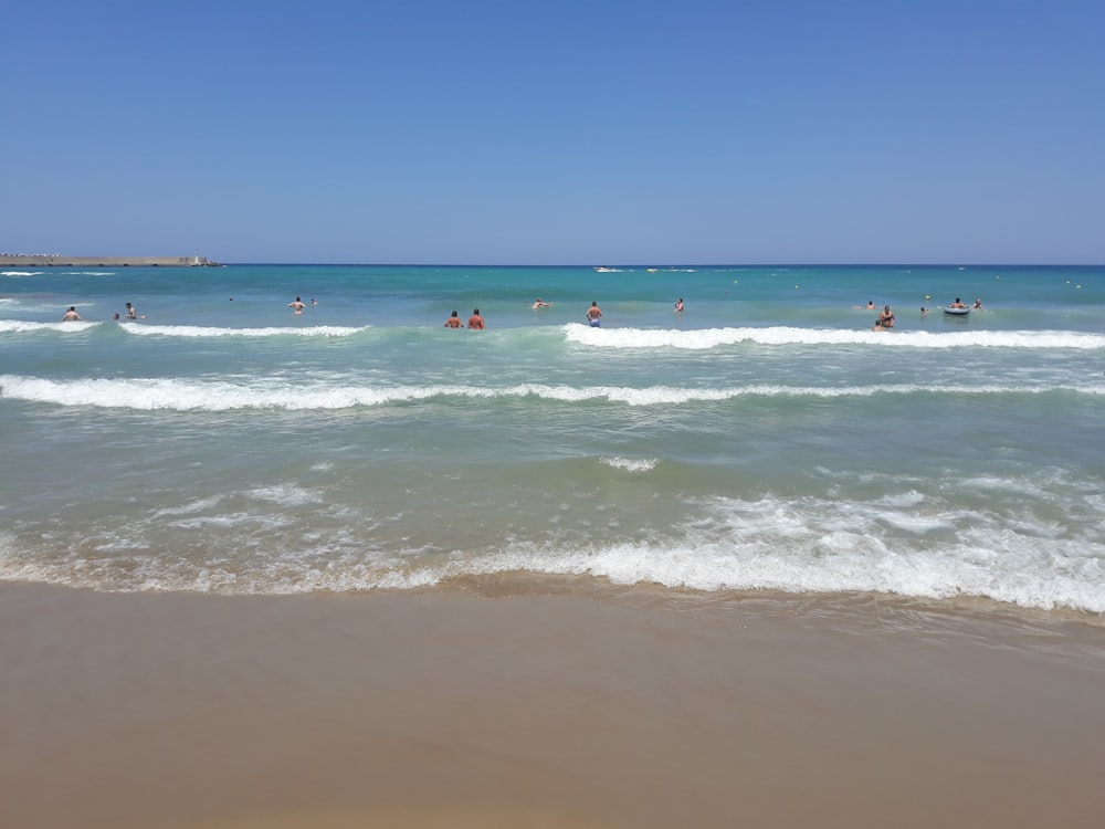 people swimming at the beach during daytime