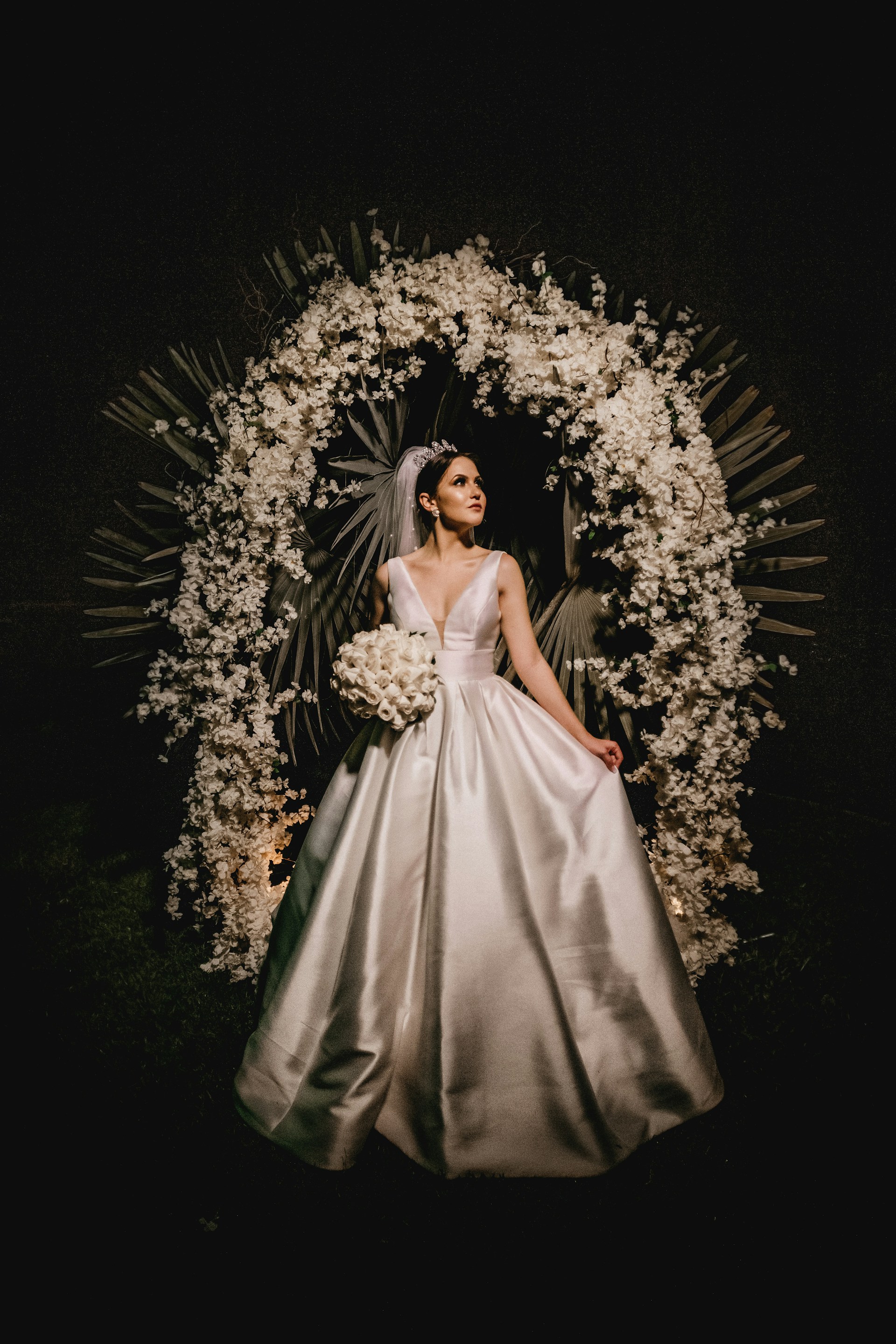 A modern wedding scene featuring a bride in a flowing gown beneath a delicate beige and gold arch, surrounded by minimalist floral arrangements and subtle Moroccan motifs.