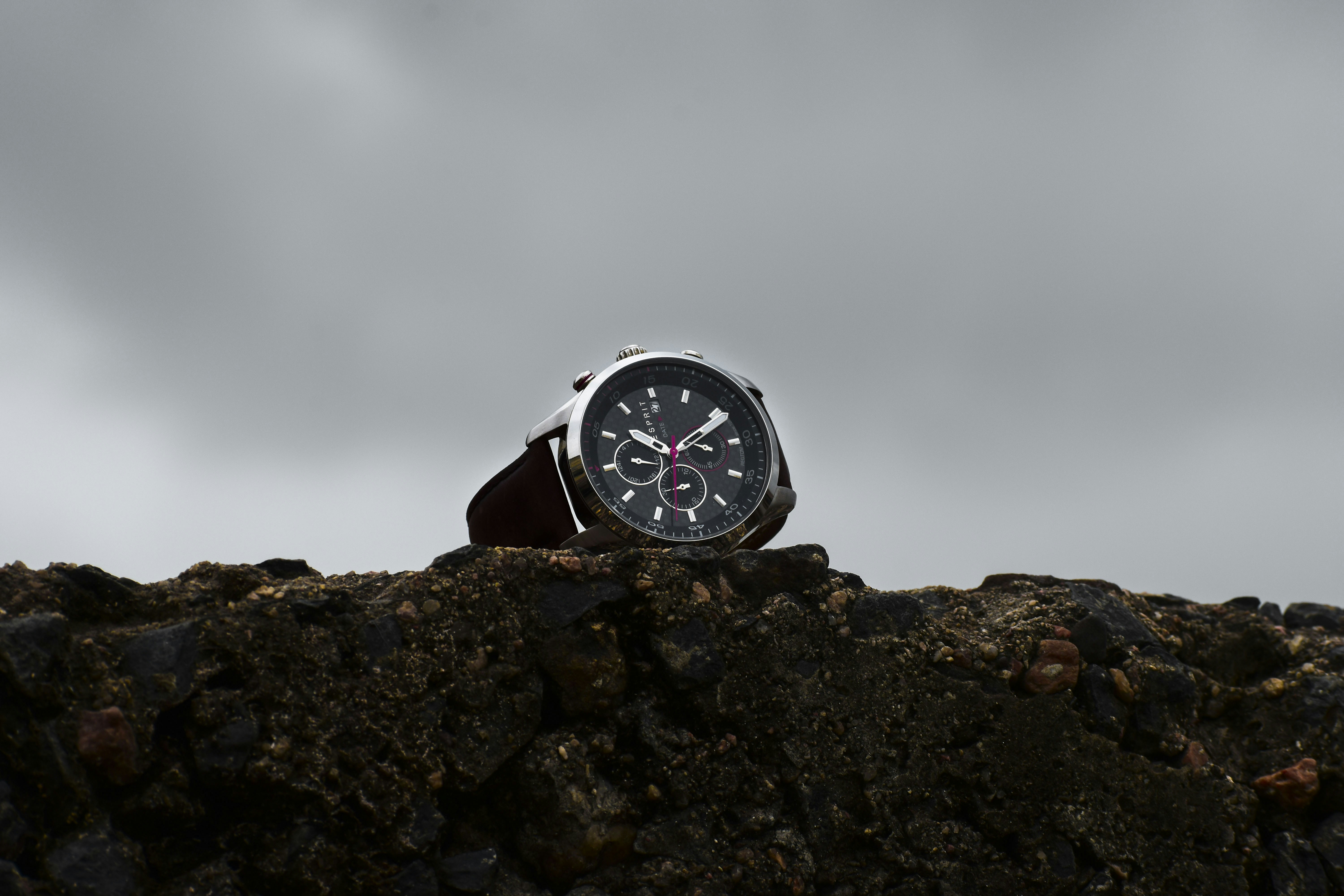 Sporty chronograph watch with black dial on dark matte background with atmospheric moody lighting