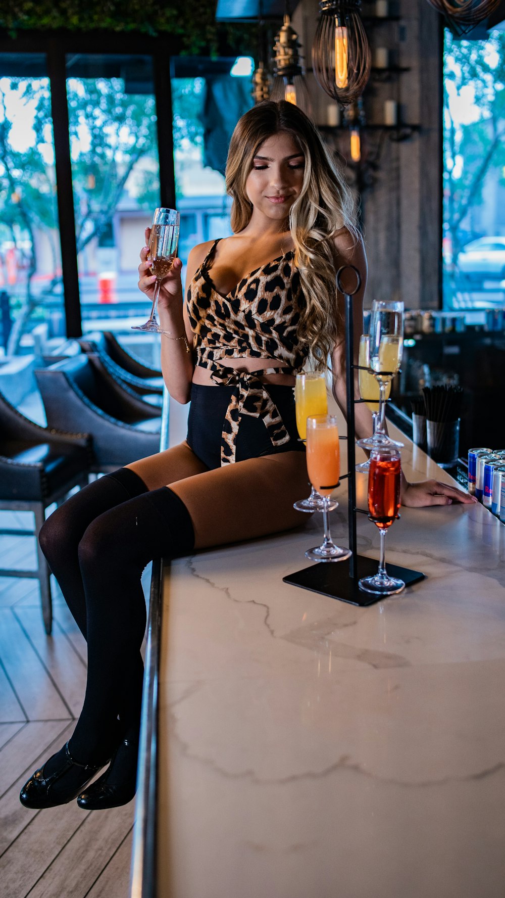 woman sitting on counter while holding champagne flute