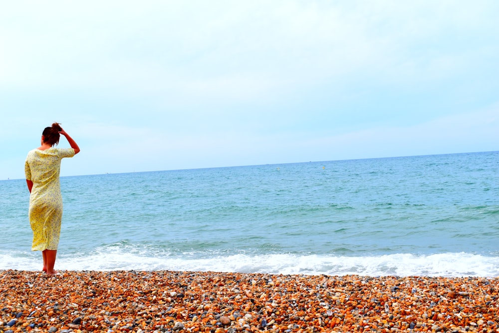 femme en jaune sur une plage rocheuse