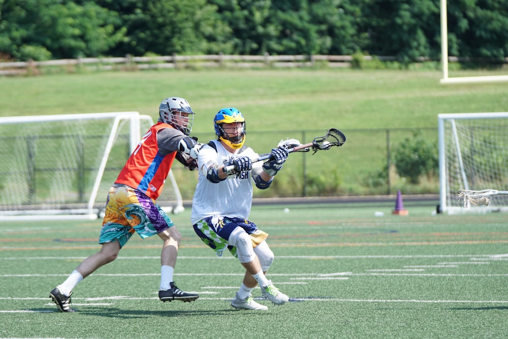 two men playing lacrosse during daytime