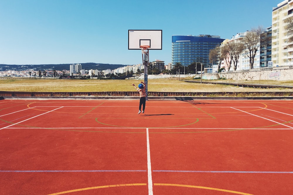 girl jumping near basketball court during daytime