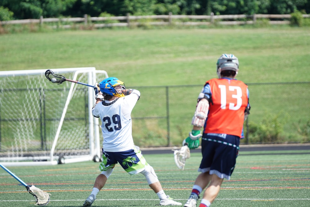 two men playing lacrosse during daytime