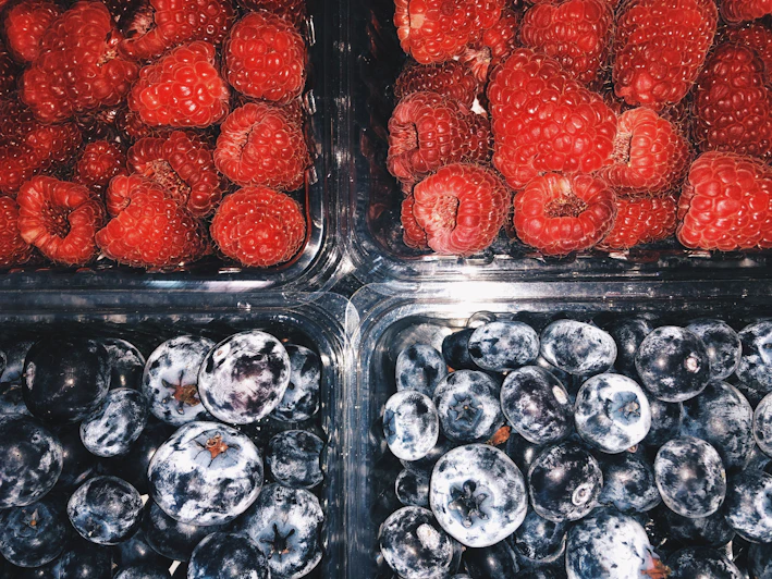 Close-up of fresh, vibrant organic berries in a rustic wooden crate highlighting deep ripe crimson hues.