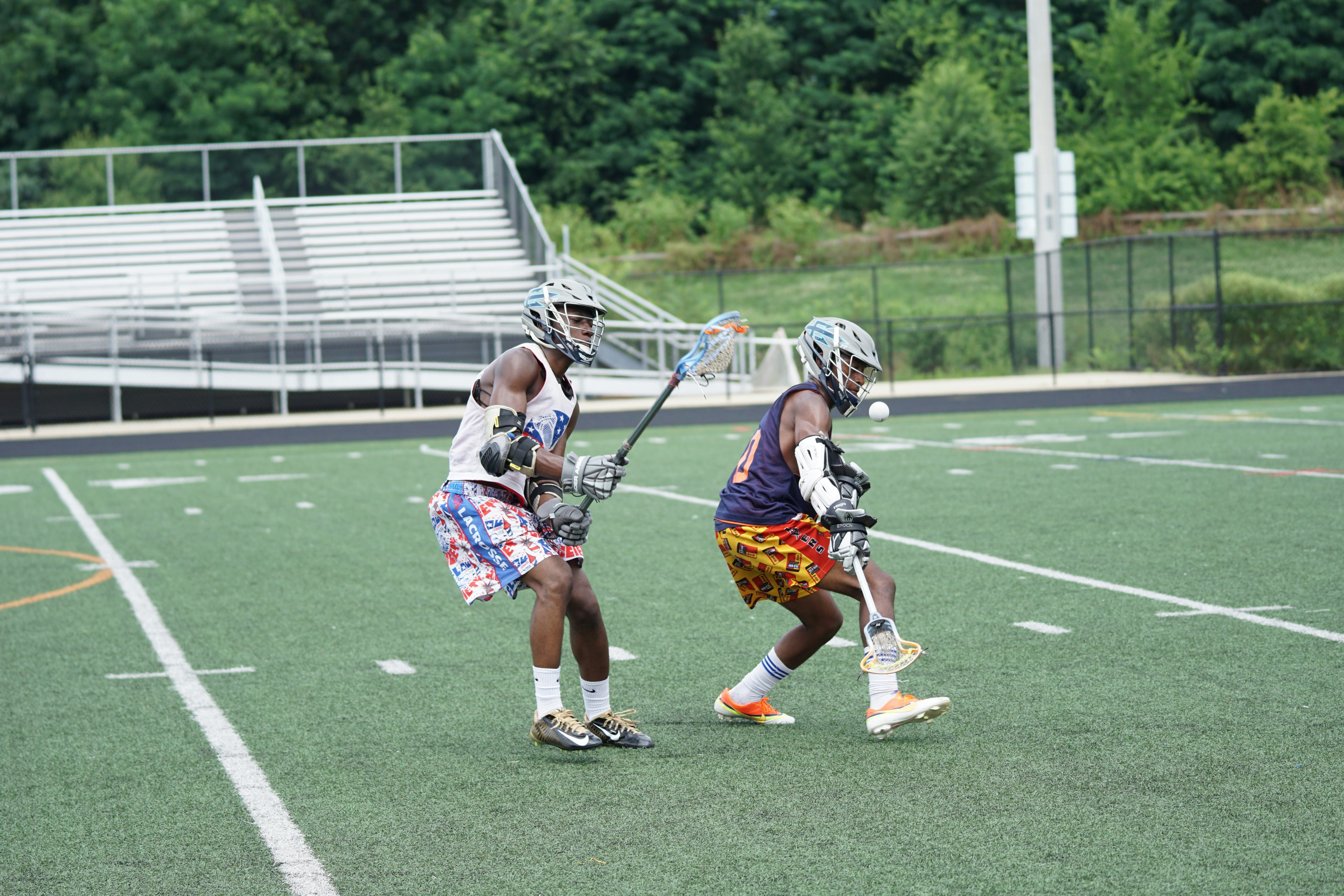 two men holding lacrosse sticks on green field